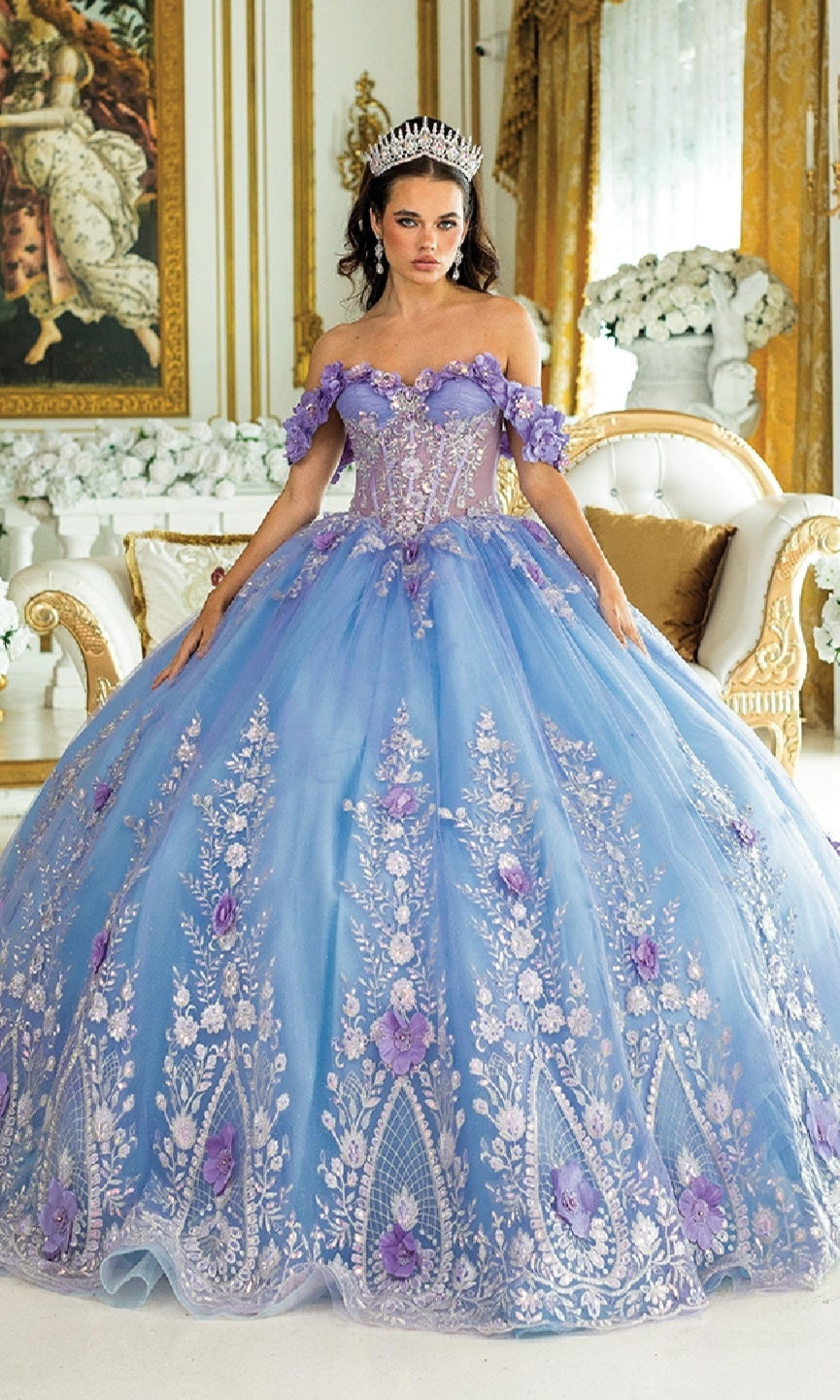 A woman in the Blue Quinceanera Dress 1999 by Dancing Queen, featuring jeweled accents and floral details, stands in an ornate room with gold and white décor.